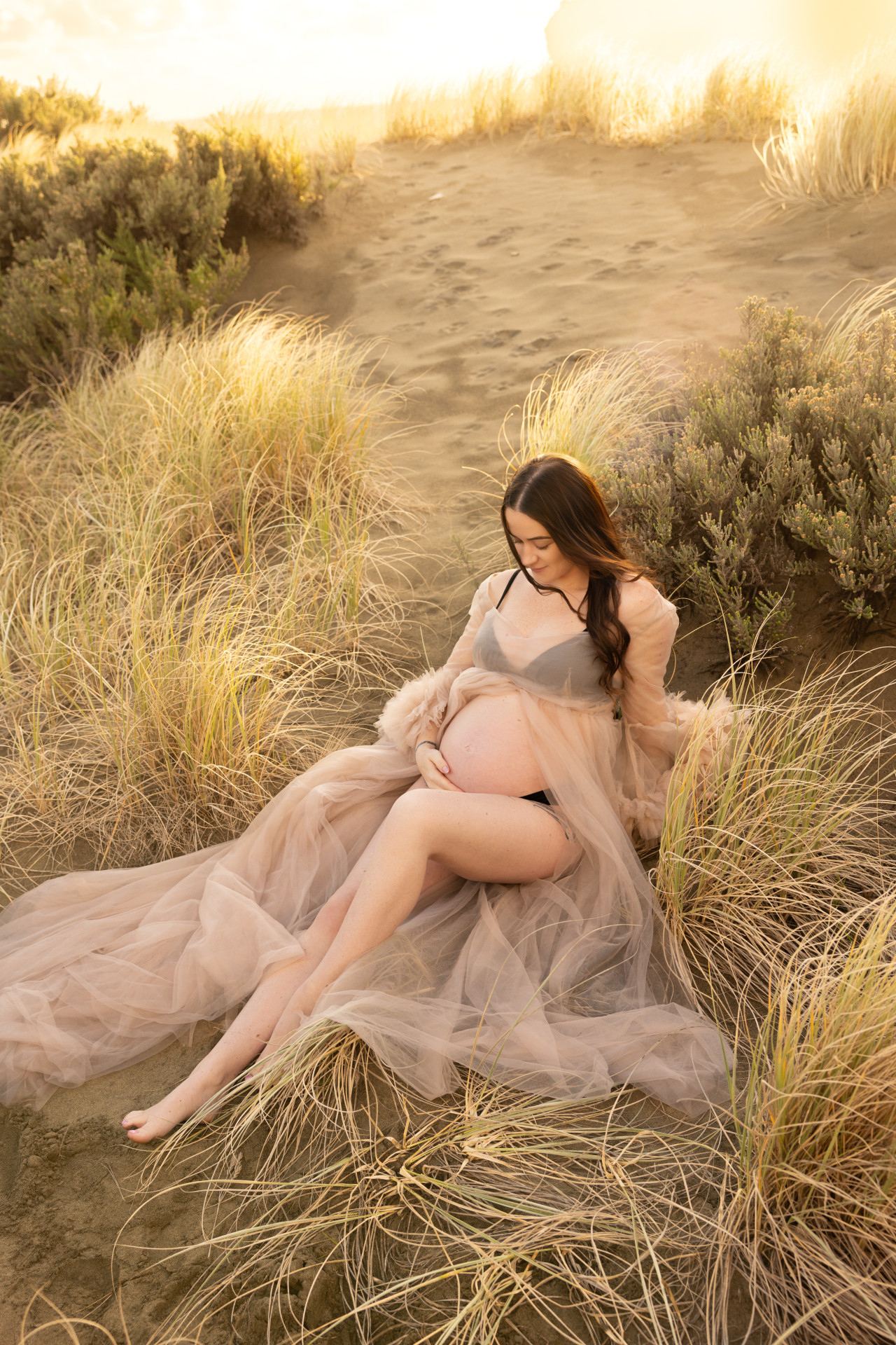 pregnant woman sitting in golden grass