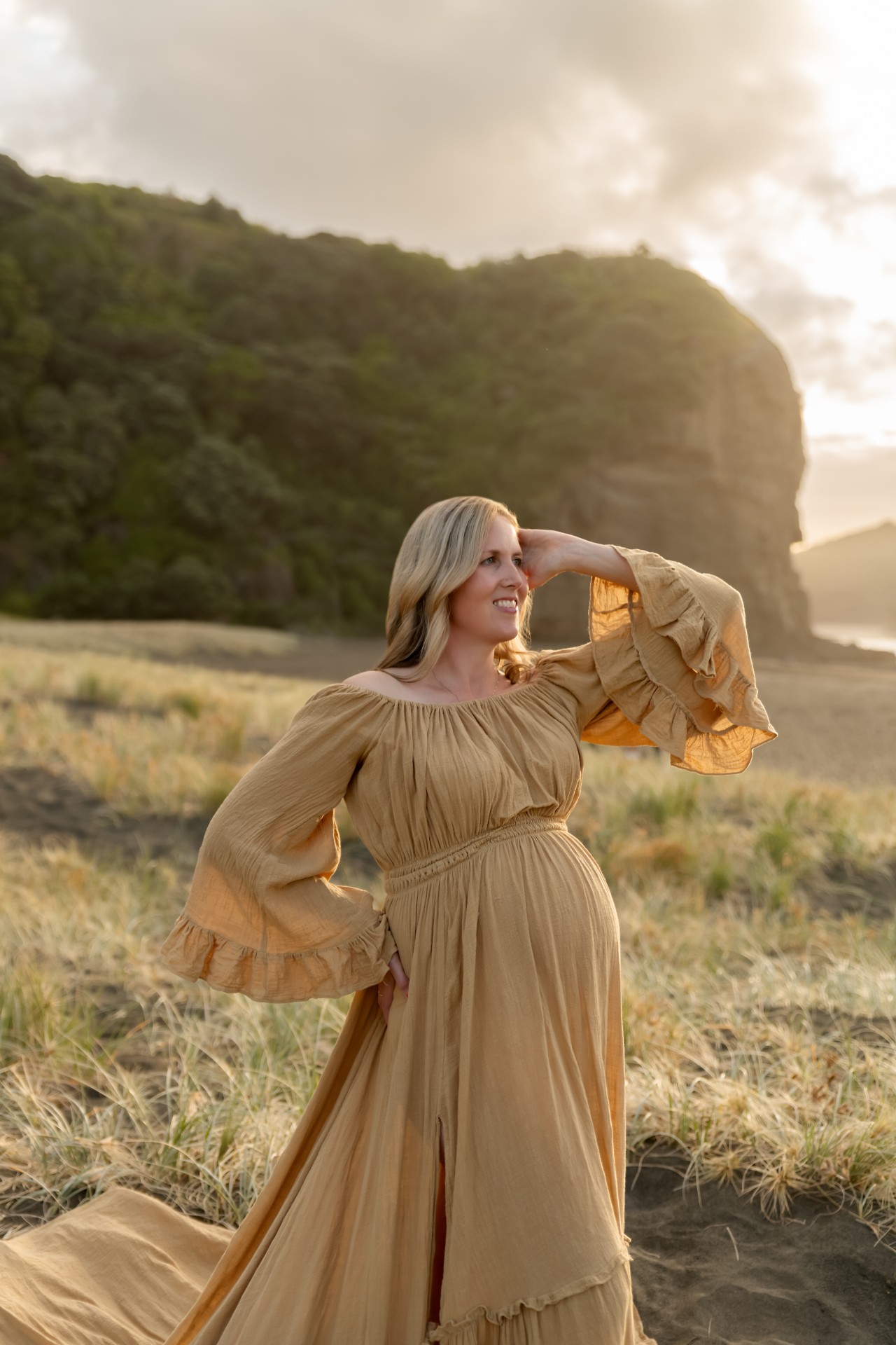 maternity session on piha beach, with auckland maternity photographer. lady is wearing long boho gown