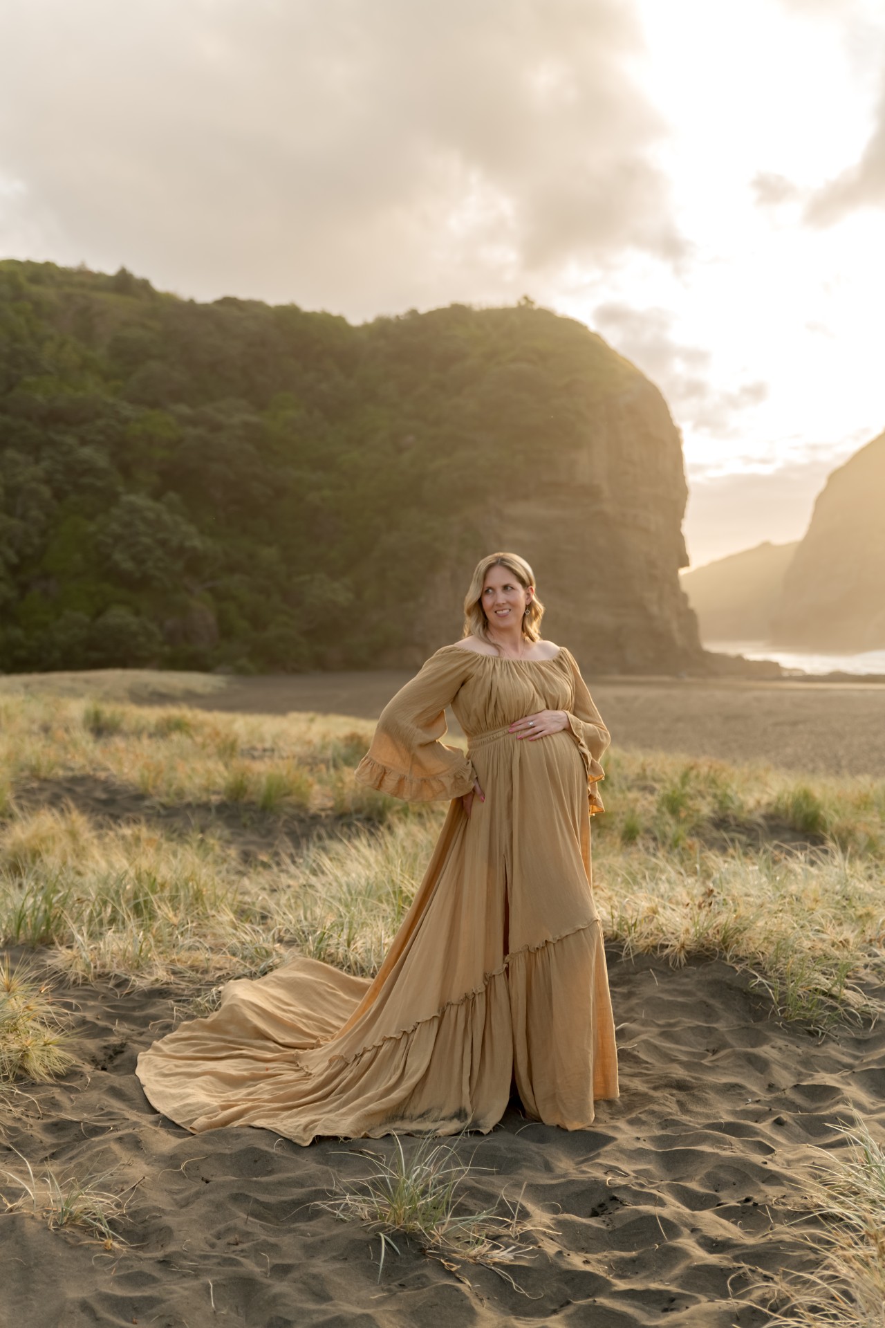 pregnant woman in yellow gown with the long trail on the piha beach