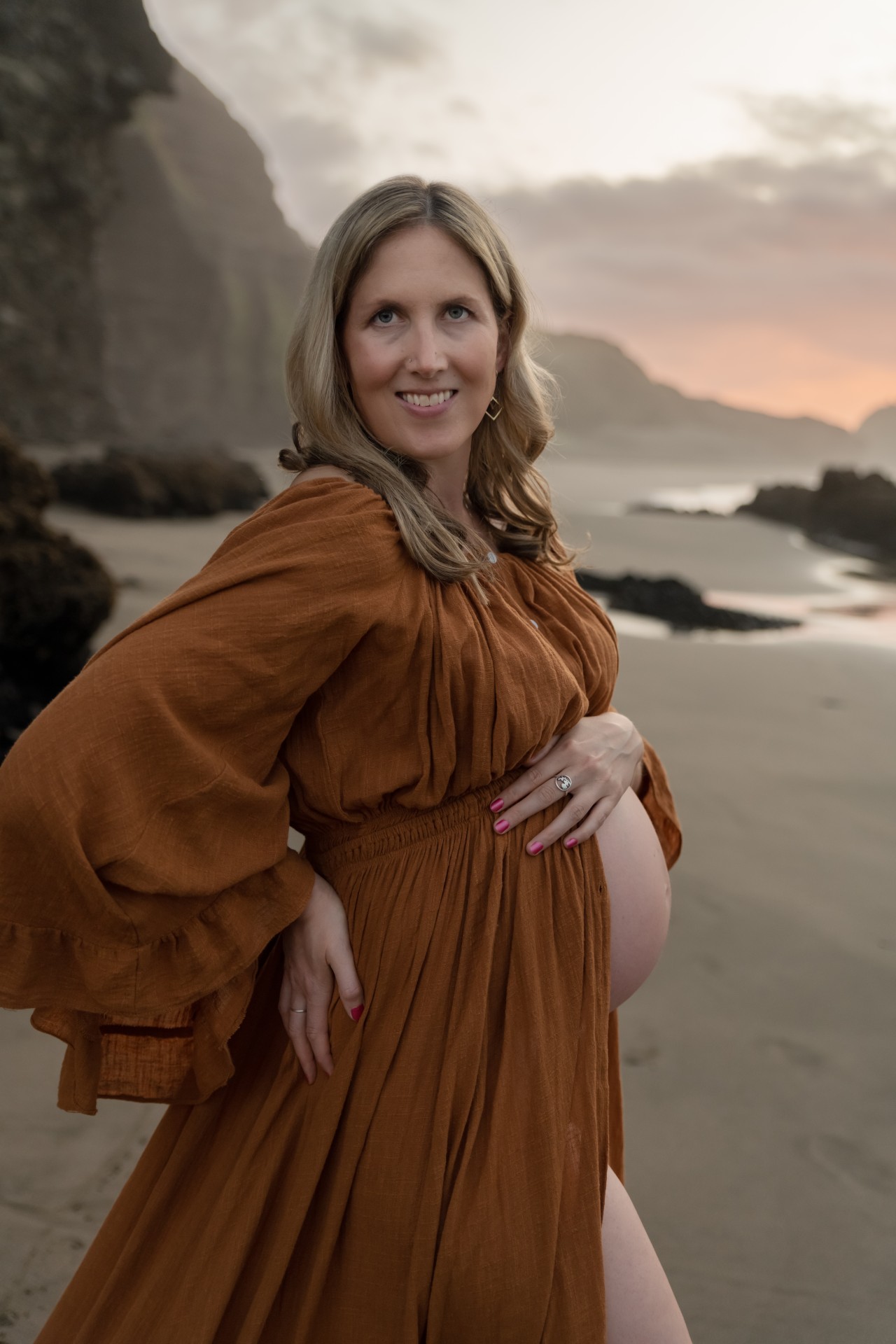 woman is showing a pregnant belly and wearing a long gown