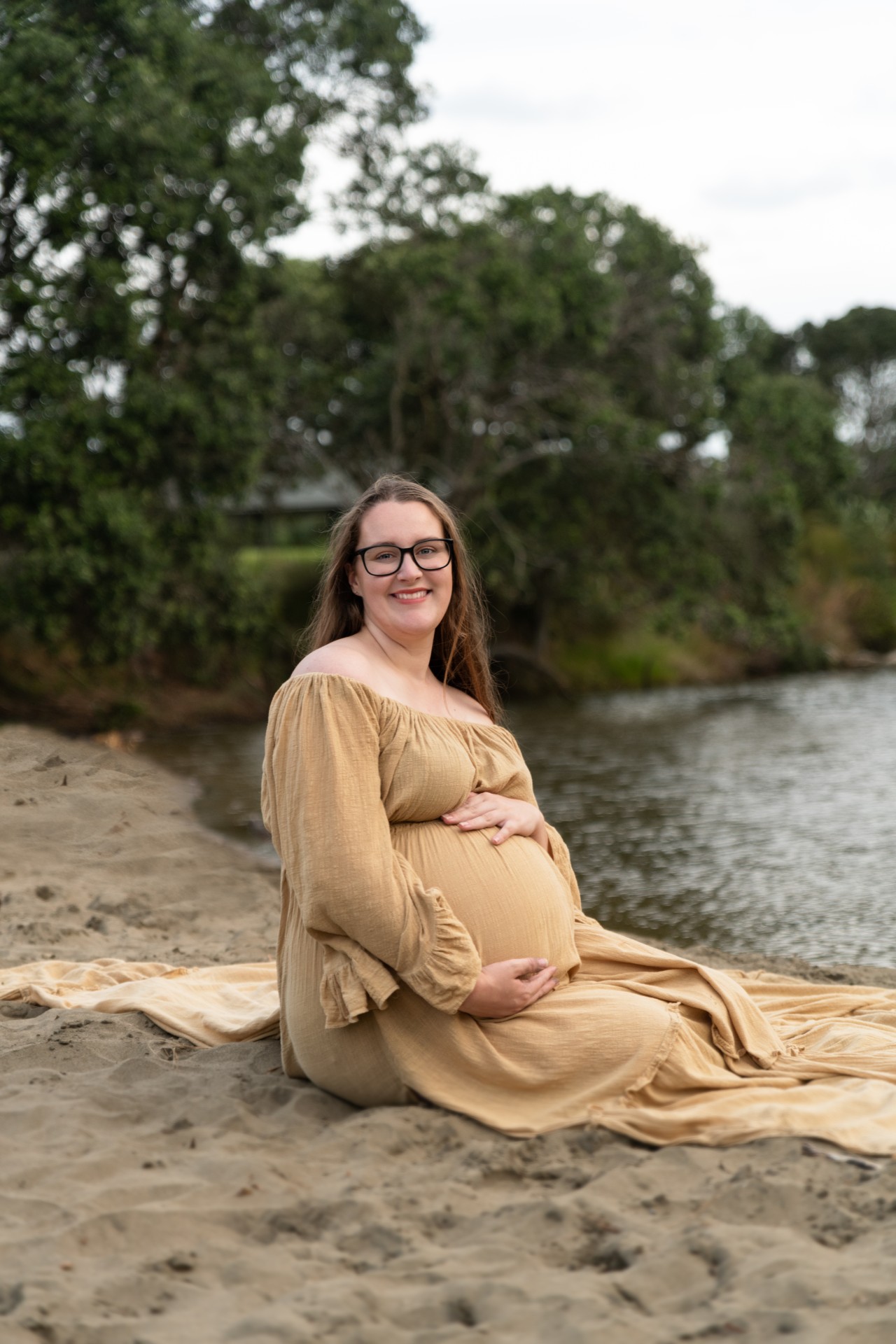 pregnant lady sitting on the beach in yellow maternity gown