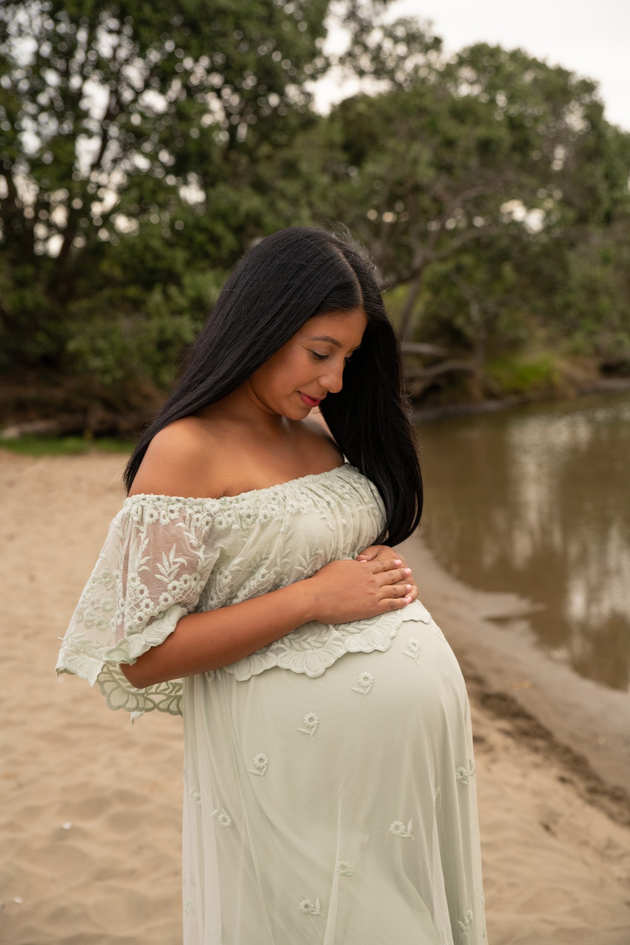 pregnant woman on the beach wearing sage lace gown
