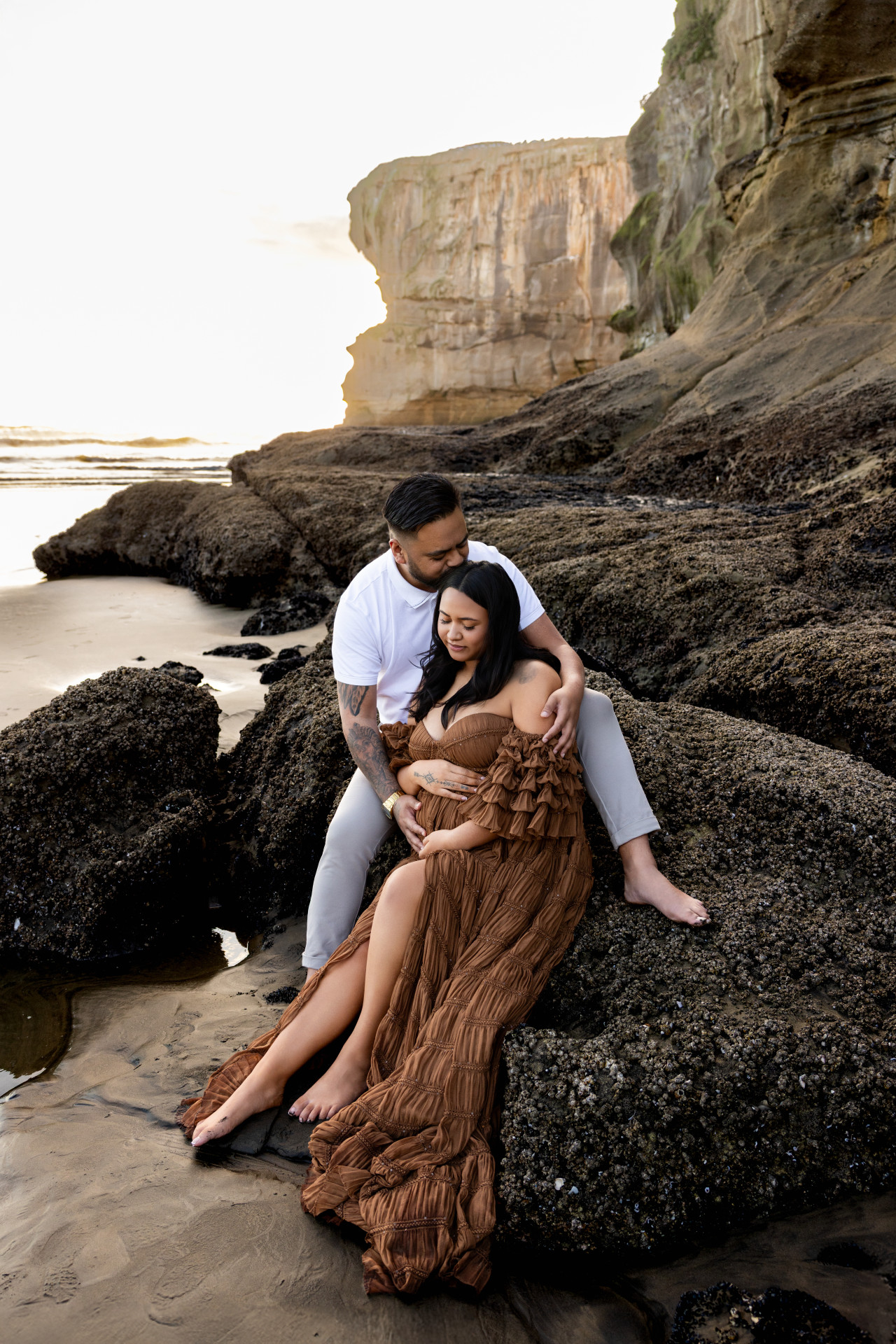 pregnant mama and dad sitting on the rocks