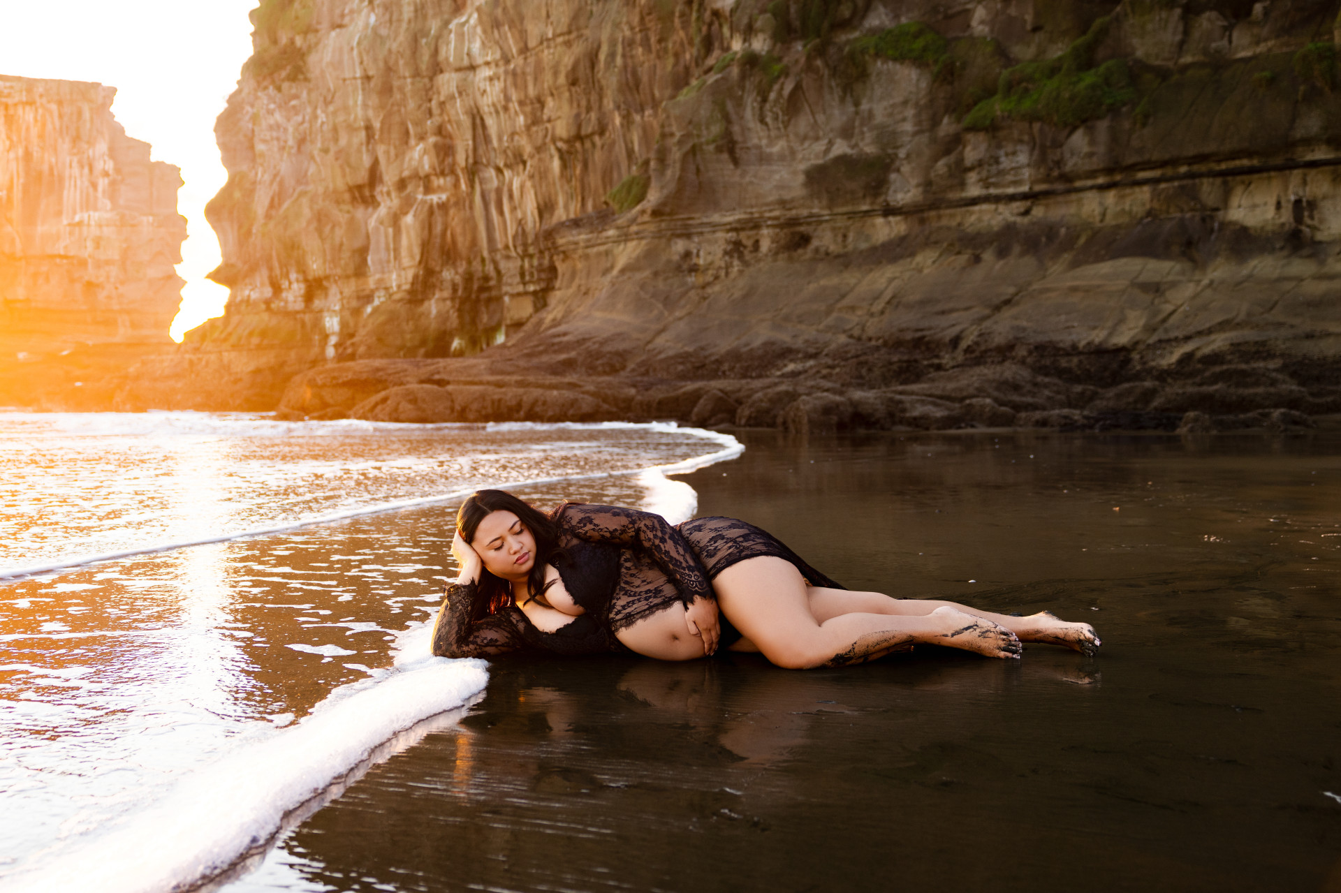 pregnant woman laying in the sand at the beach
