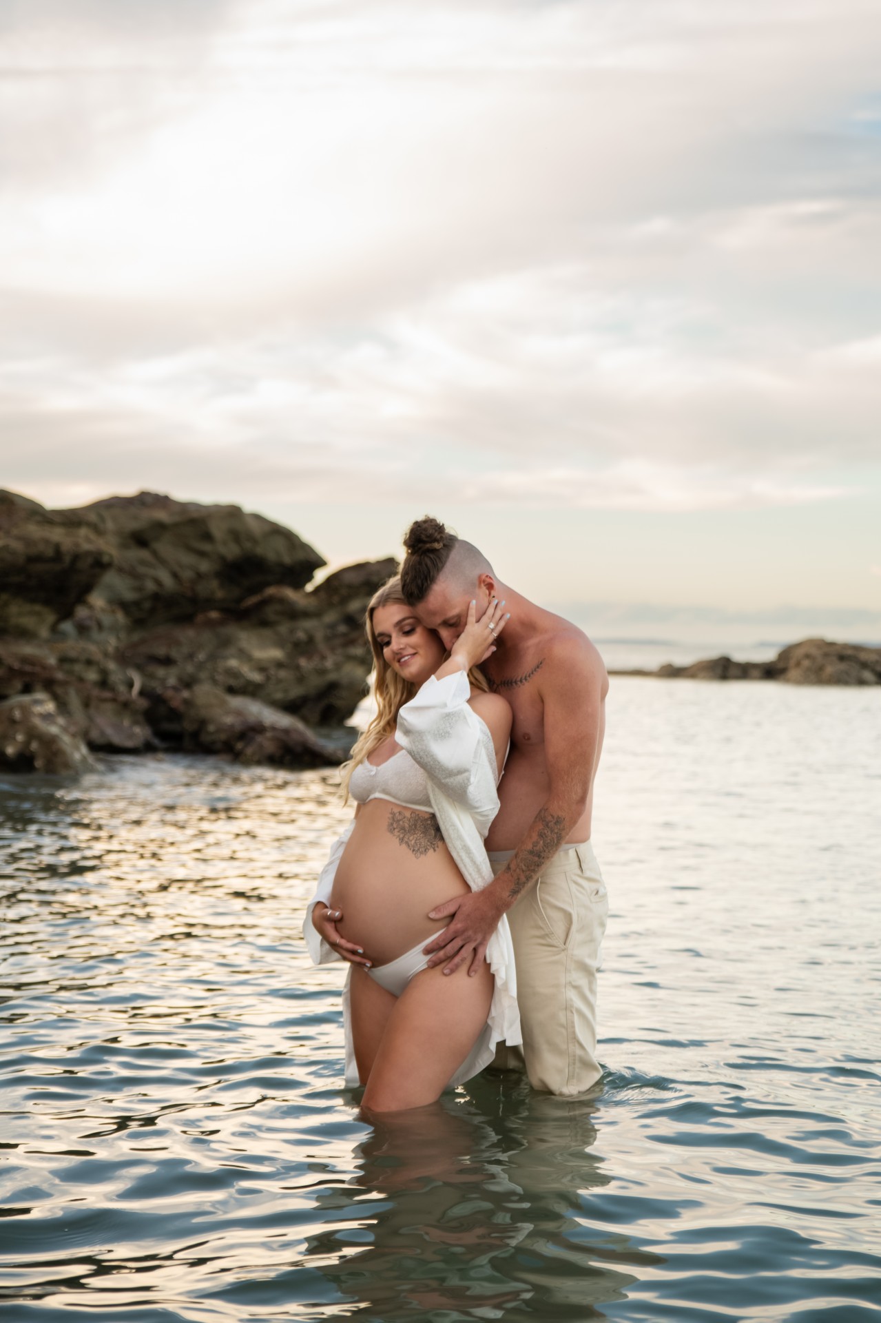 couple with a pregnant belly is standing in the water