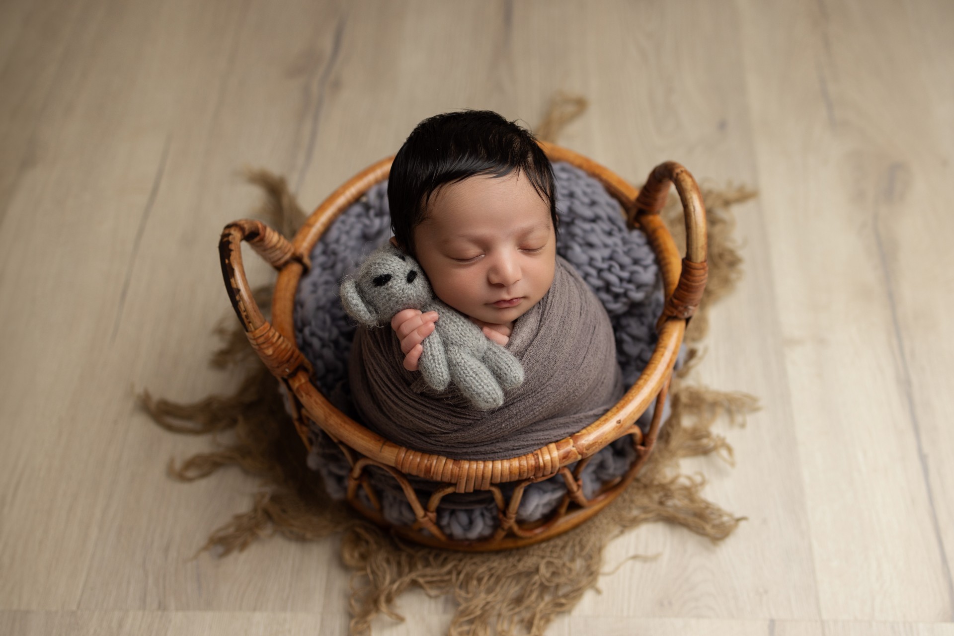 newborn in basket holding teddy