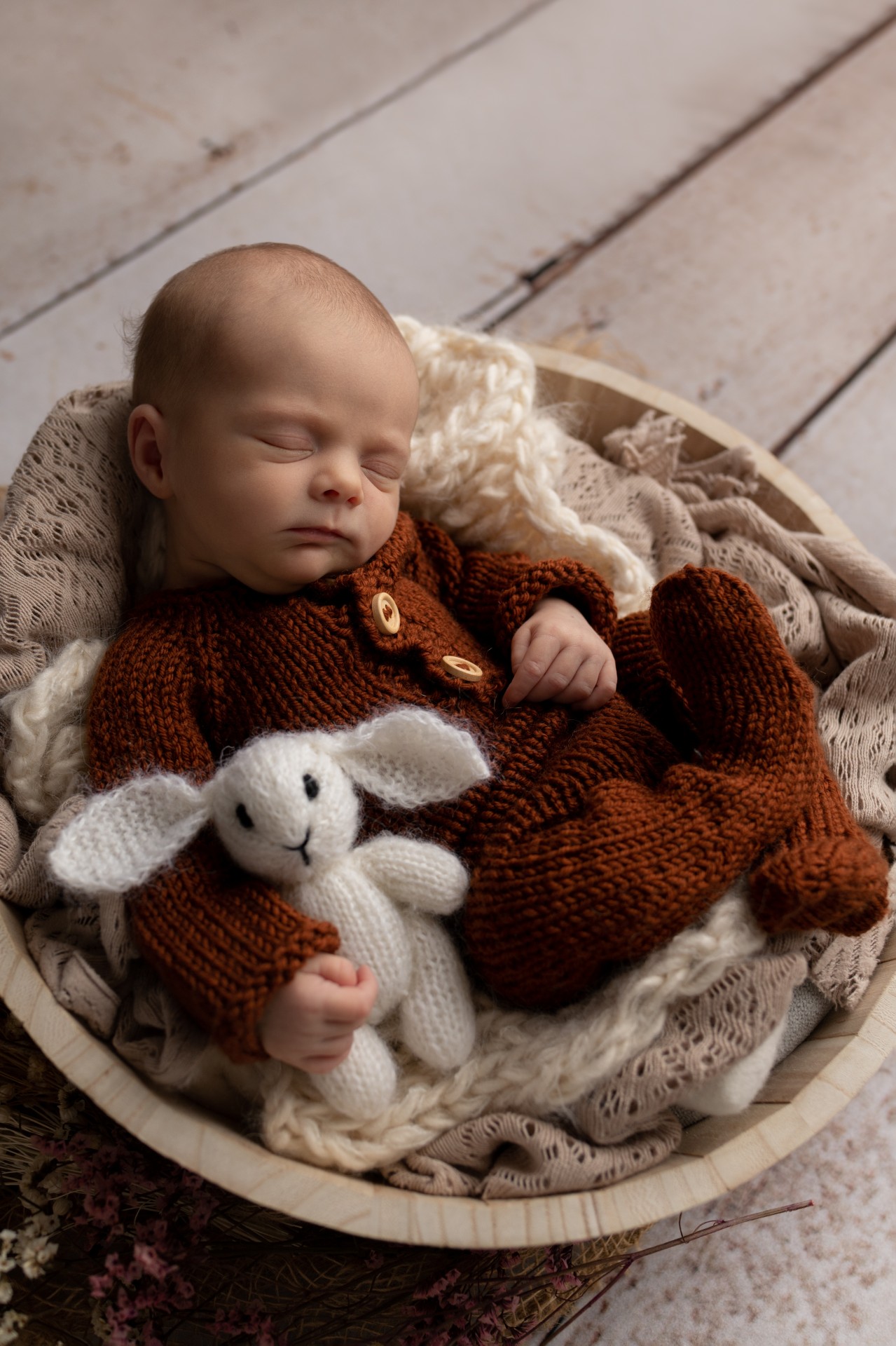 newborn girl in the rust knitted outfit cuddling the rabbit toy