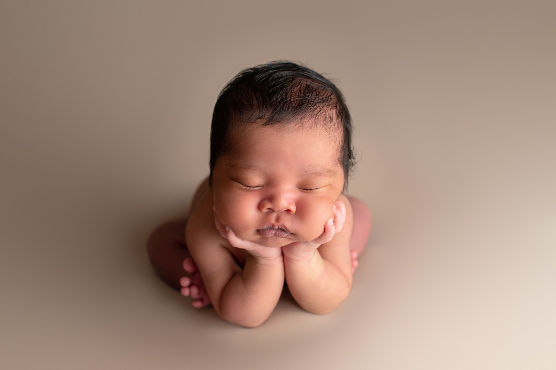 baby with dark hair is sleeping in the newborn froggy pose