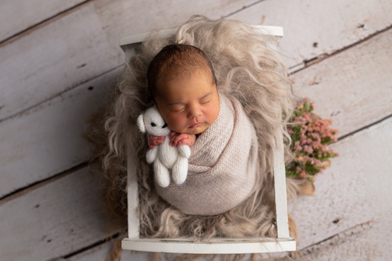 baby girl wraped in the rose knitted wrap holding a cudly