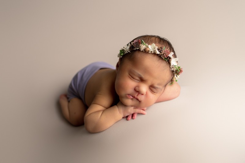 newborn sleeping on the hands and wearing a floral crown