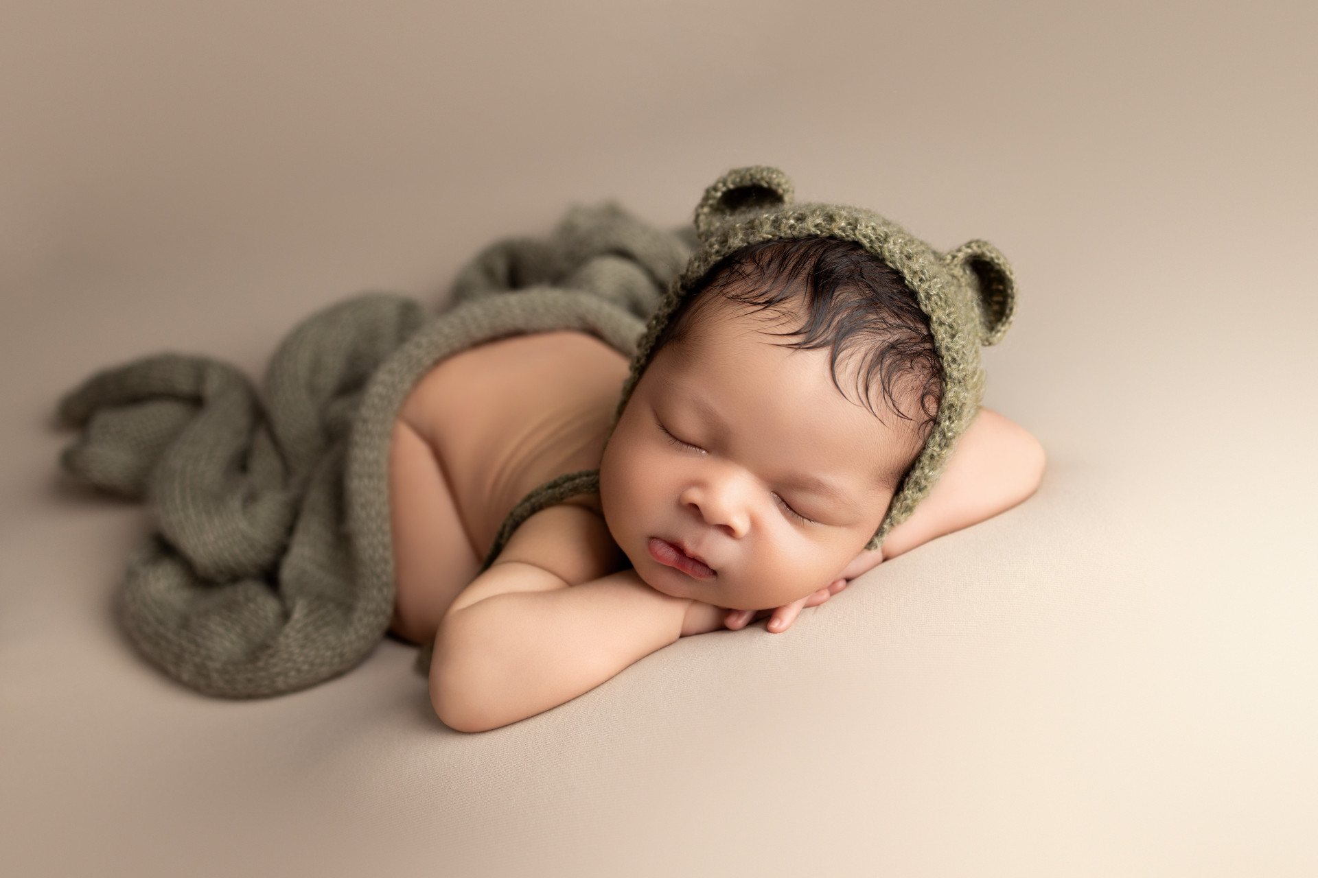 newborn sleeping wearing teddy bonnet