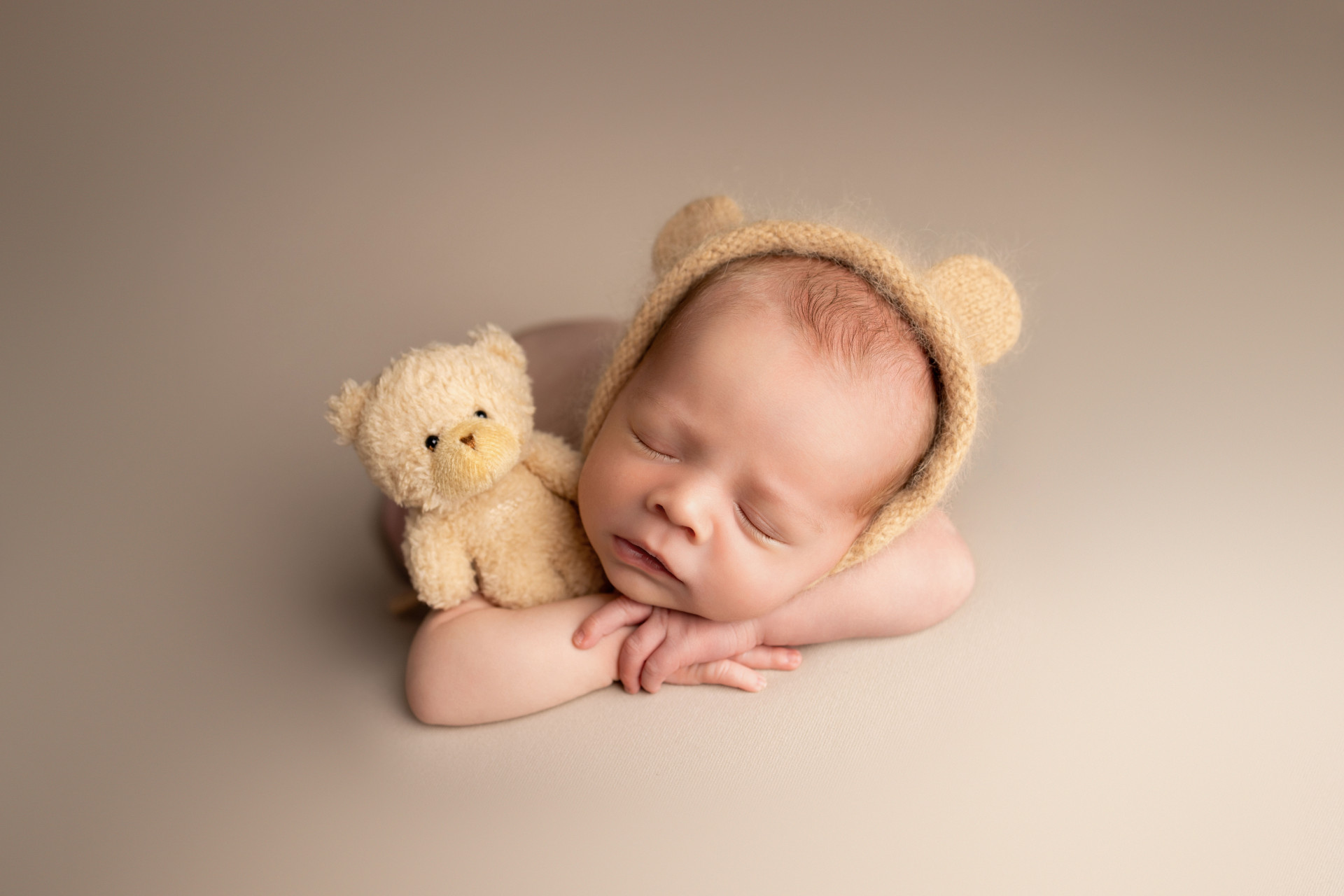 baby sleeping on his hands cuddling teddy